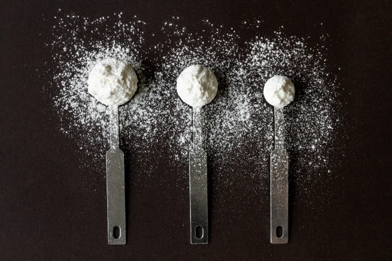 Three stainless steel scoops of sugar free protein powder showing Organic Innovation’s clean natural grass fed whey protein without artificial sweeteners.